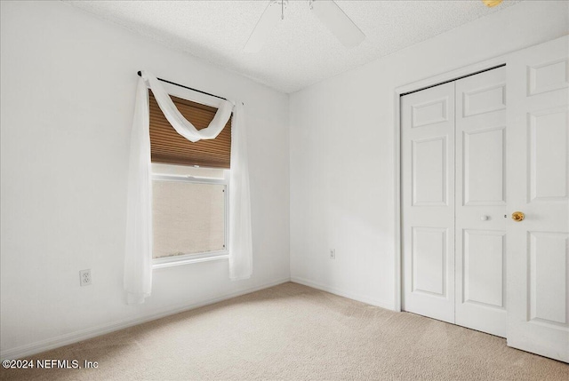 unfurnished bedroom with a closet, carpet, a textured ceiling, ceiling fan, and baseboards