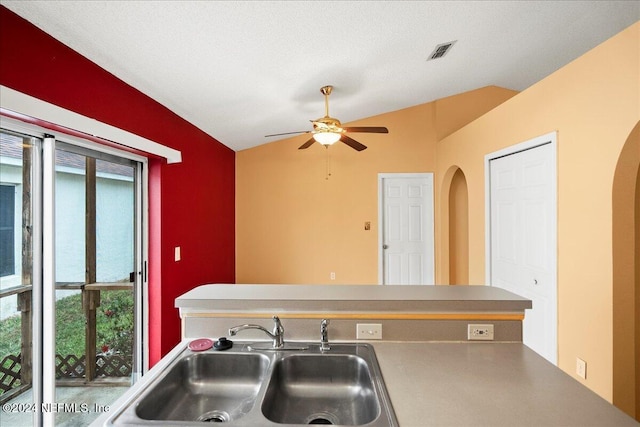 kitchen featuring lofted ceiling, a textured ceiling, sink, and ceiling fan