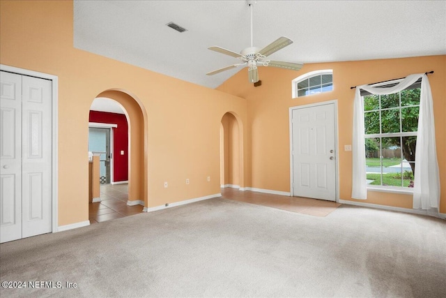 interior space with lofted ceiling, a textured ceiling, light colored carpet, and ceiling fan