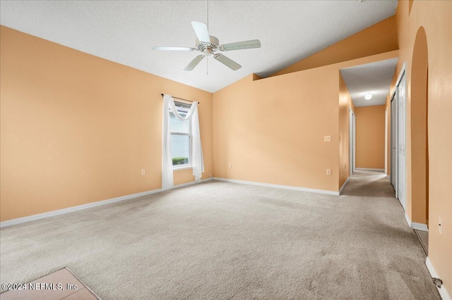 unfurnished room featuring lofted ceiling, carpet flooring, ceiling fan, a textured ceiling, and baseboards