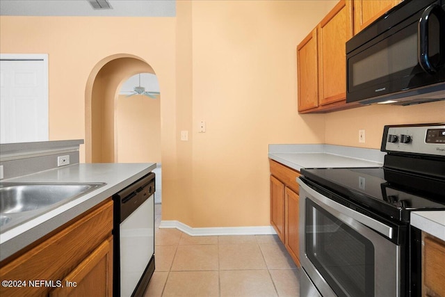 kitchen featuring black microwave, stainless steel electric range oven, dishwasher, arched walkways, and brown cabinets