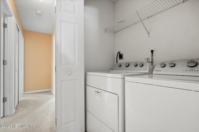 clothes washing area featuring separate washer and dryer, light colored carpet, and baseboards