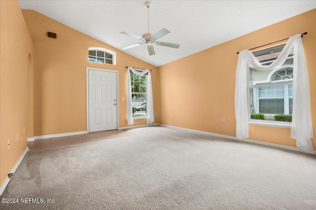 carpeted empty room featuring a textured ceiling, high vaulted ceiling, and ceiling fan