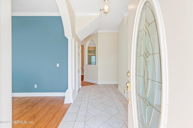 foyer entrance featuring ornamental molding, decorative columns, and light hardwood / wood-style floors