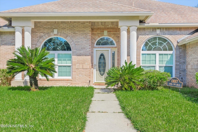 view of exterior entry featuring a yard