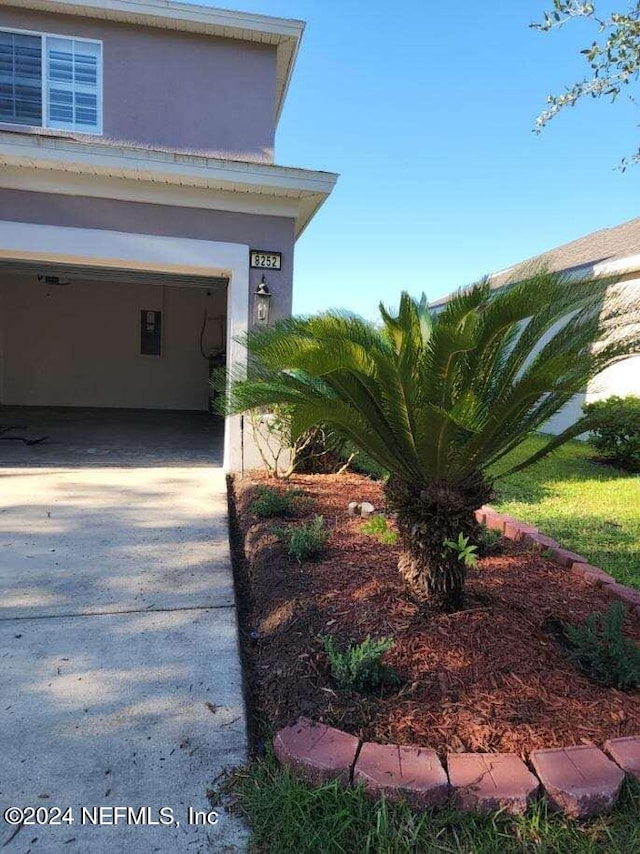 view of side of property with a garage, driveway, and stucco siding