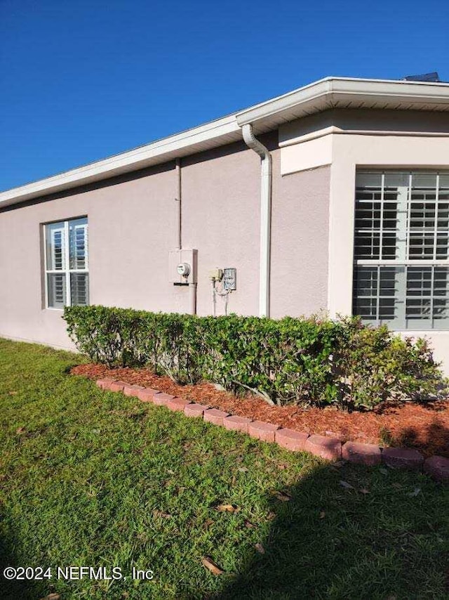 view of side of property with a yard and stucco siding