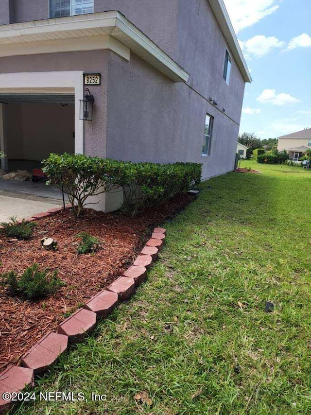 view of home's exterior with concrete driveway, a lawn, and stucco siding