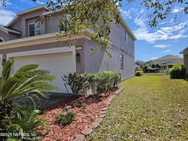 view of side of property with a garage, a yard, and stucco siding