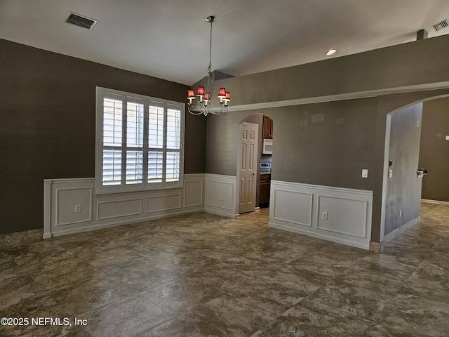 unfurnished dining area featuring arched walkways, vaulted ceiling, visible vents, and a decorative wall