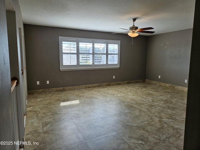 empty room featuring a ceiling fan, a textured ceiling, and baseboards