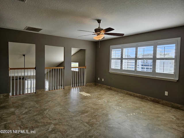 unfurnished room featuring a ceiling fan, visible vents, a textured ceiling, and baseboards