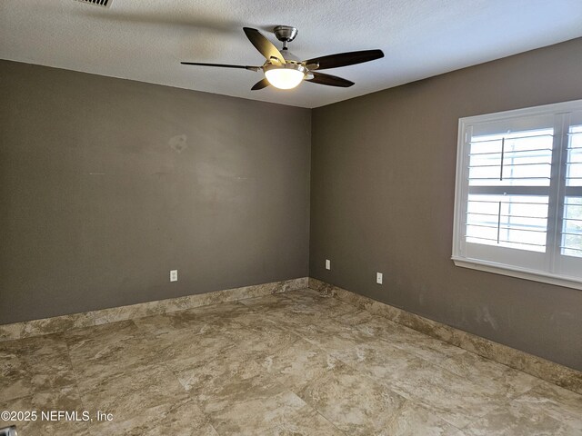 empty room with a ceiling fan and a textured ceiling