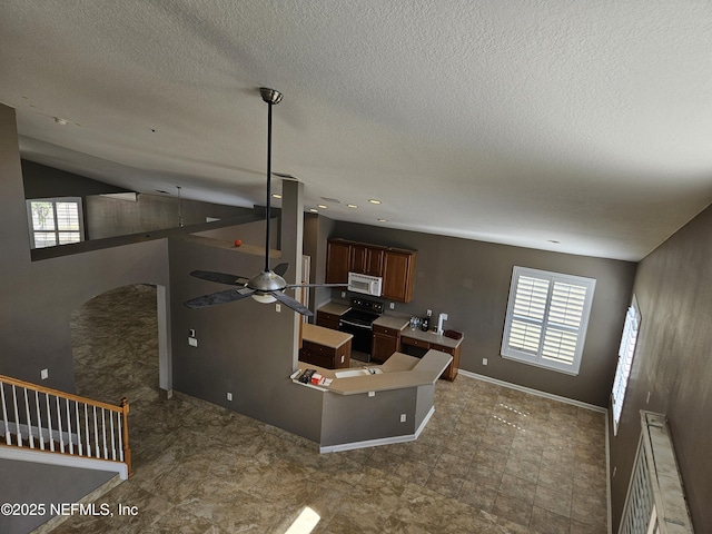 kitchen with baseboards, a ceiling fan, white microwave, black electric range oven, and vaulted ceiling