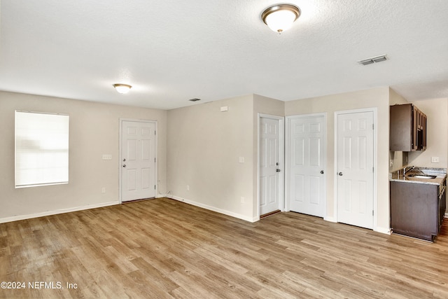 interior space featuring a textured ceiling, sink, and light hardwood / wood-style flooring