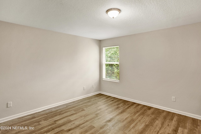 spare room featuring light hardwood / wood-style floors and a textured ceiling