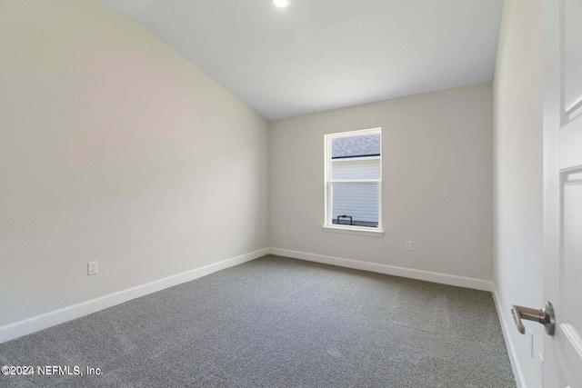 carpeted spare room with vaulted ceiling