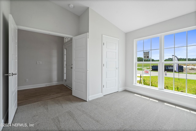 unfurnished bedroom featuring lofted ceiling and carpet