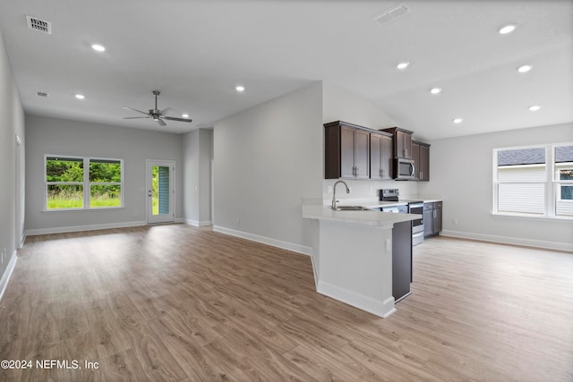 kitchen featuring a peninsula, a sink, visible vents, open floor plan, and appliances with stainless steel finishes