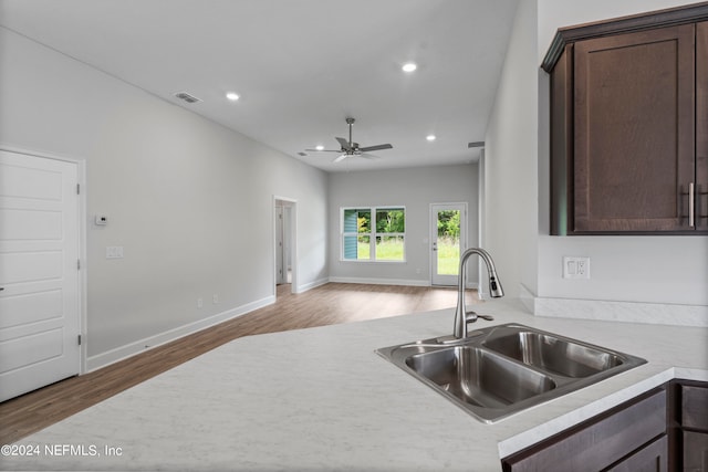 kitchen featuring light countertops, wood finished floors, a sink, and recessed lighting