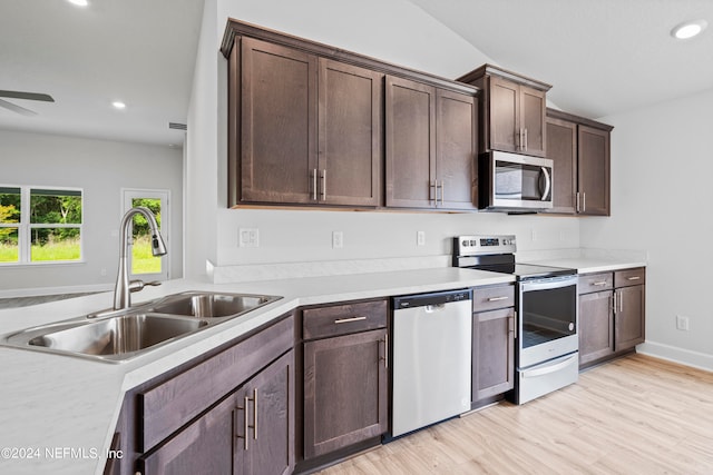 kitchen with stainless steel appliances, light countertops, a sink, and dark brown cabinetry