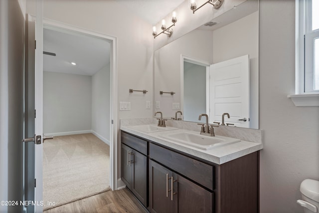 bathroom featuring double vanity, a sink, visible vents, and baseboards