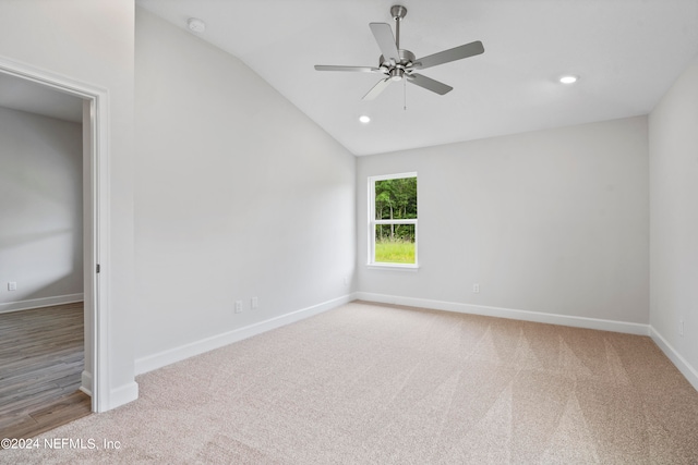 empty room featuring carpet floors, recessed lighting, vaulted ceiling, and baseboards