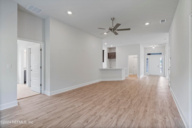 unfurnished living room featuring light wood-type flooring, visible vents, ceiling fan, and baseboards