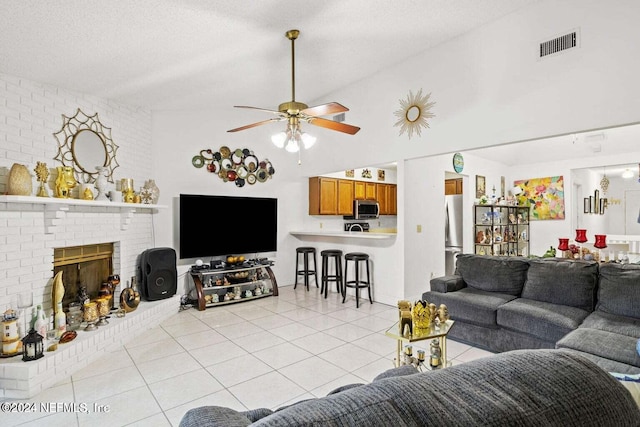 tiled living room featuring ceiling fan, a textured ceiling, and a fireplace