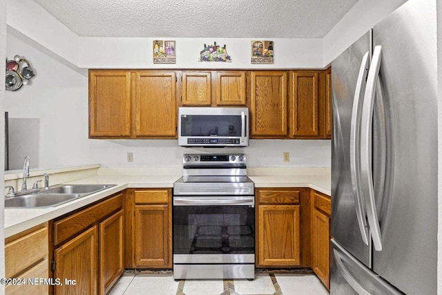 kitchen featuring a textured ceiling, stainless steel appliances, sink, and light tile patterned floors