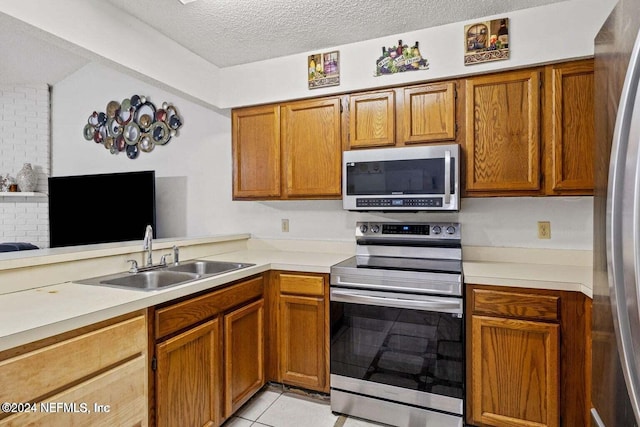 kitchen featuring appliances with stainless steel finishes, sink, a textured ceiling, kitchen peninsula, and light tile patterned floors