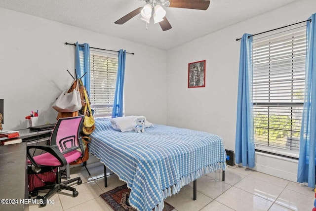 tiled bedroom with multiple windows, a textured ceiling, and ceiling fan