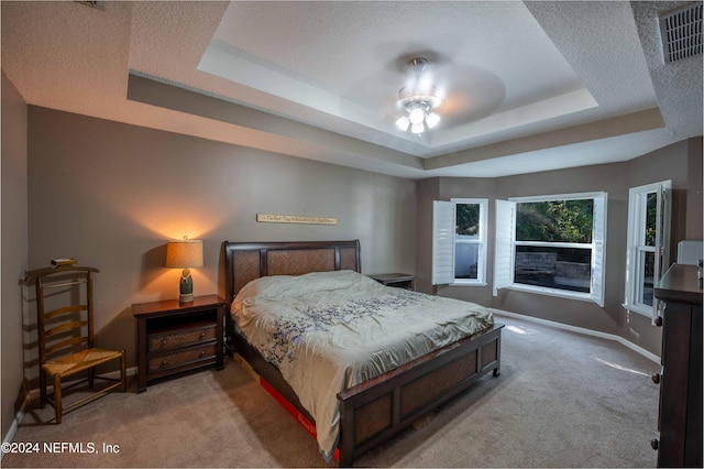 bedroom with light carpet, a tray ceiling, and ceiling fan