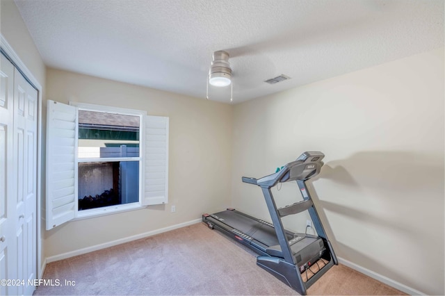 workout area with ceiling fan, carpet floors, and a textured ceiling