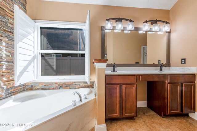 bathroom with a washtub, vanity, and tile patterned floors