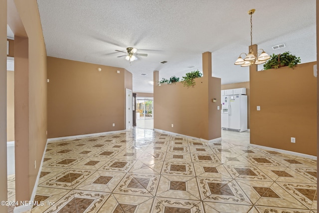 empty room with a textured ceiling, tile patterned flooring, and ceiling fan with notable chandelier