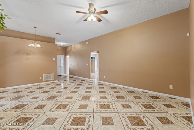 tiled empty room with a textured ceiling and ceiling fan with notable chandelier