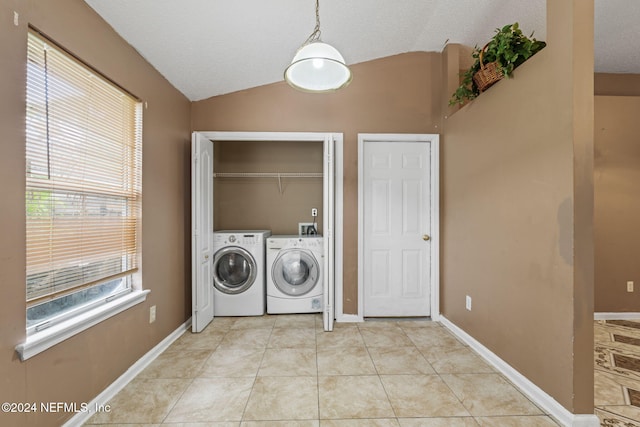 clothes washing area with washer and dryer, a textured ceiling, and light tile patterned floors