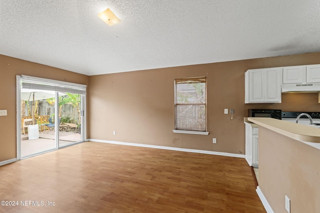 kitchen featuring white cabinets, a textured ceiling, wood-type flooring, and range with electric cooktop