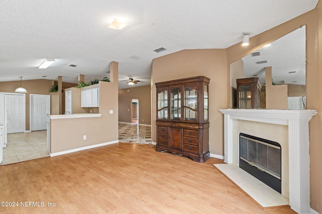 unfurnished living room with lofted ceiling, a textured ceiling, light wood-type flooring, and ceiling fan