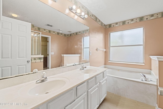 bathroom with vanity, a relaxing tiled tub, a textured ceiling, and tile patterned floors