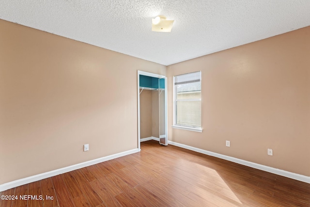 unfurnished bedroom featuring a textured ceiling, hardwood / wood-style flooring, and a closet