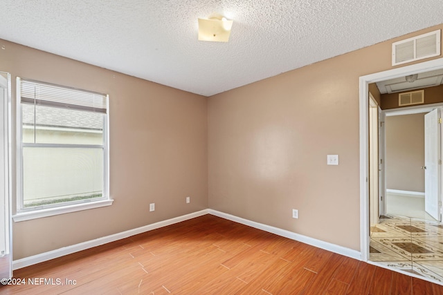 spare room with a textured ceiling and hardwood / wood-style flooring