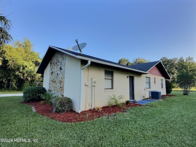 view of side of property with central air condition unit and a lawn