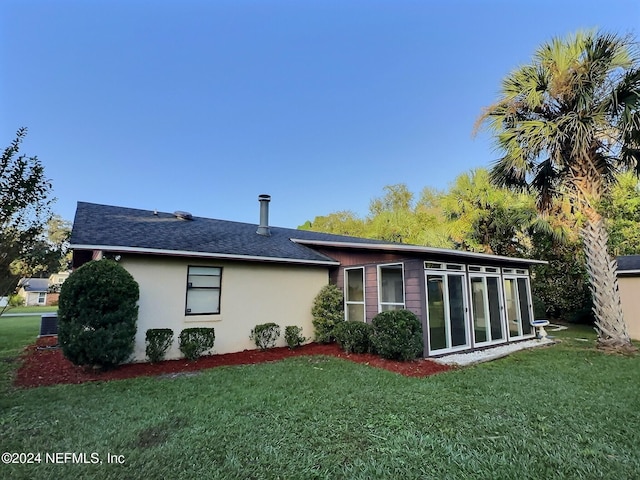 rear view of house featuring a sunroom and a lawn