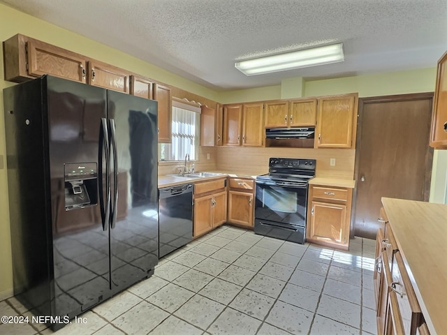 kitchen with tasteful backsplash, light tile patterned floors, a textured ceiling, black appliances, and sink