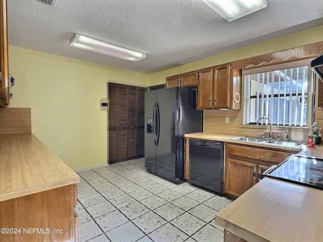 kitchen with black appliances, light tile patterned flooring, sink, a textured ceiling, and decorative backsplash