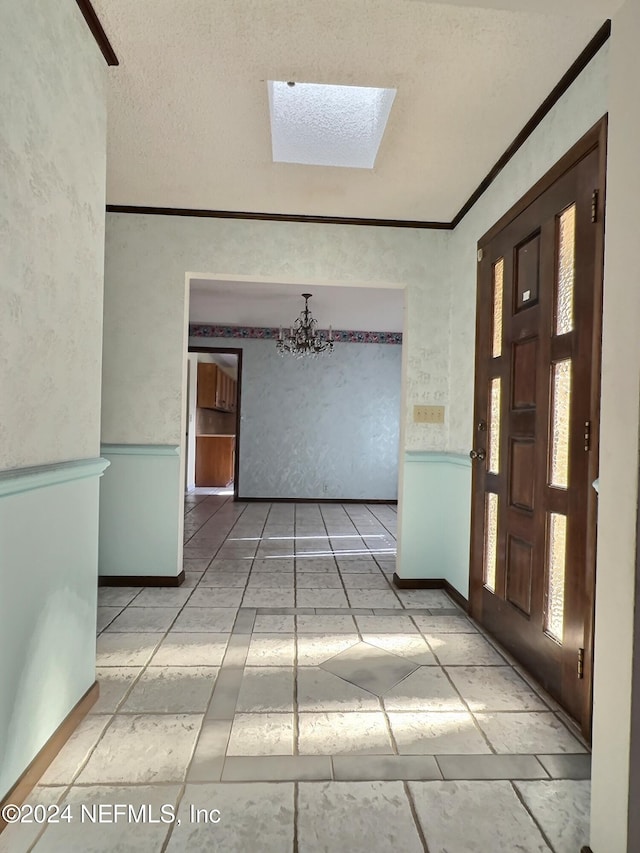 hallway featuring ornamental molding, an inviting chandelier, a textured ceiling, and a skylight