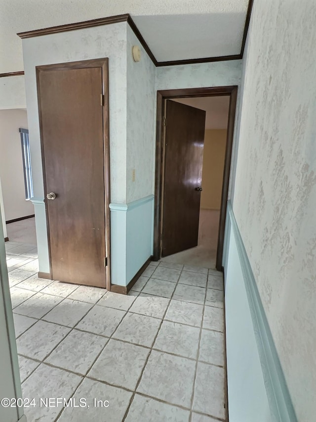 hall with ornamental molding and light tile patterned flooring