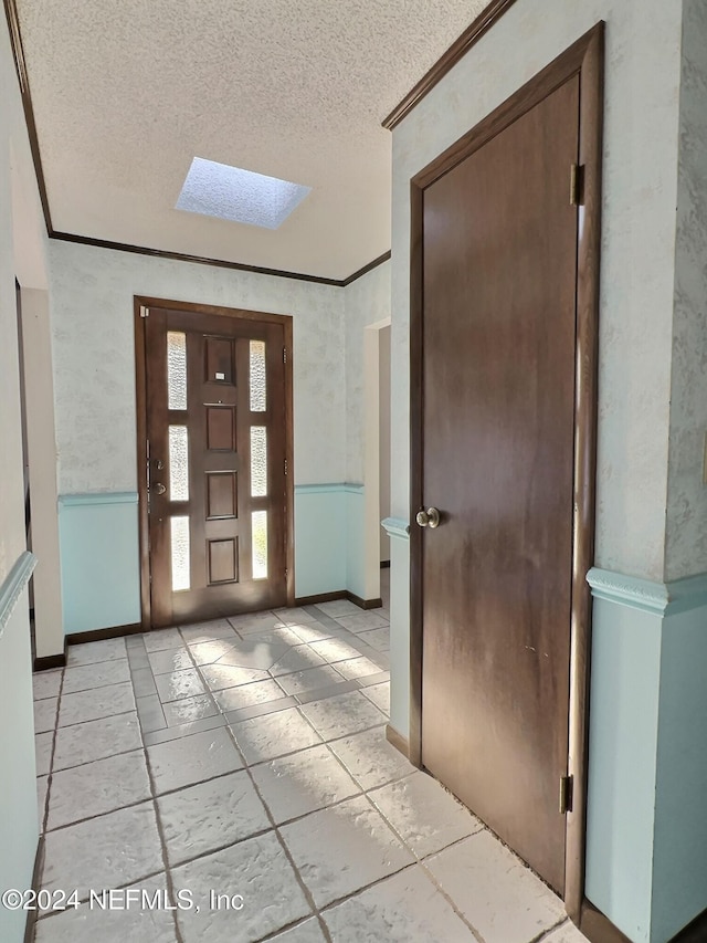 foyer entrance with crown molding, a textured ceiling, and a skylight